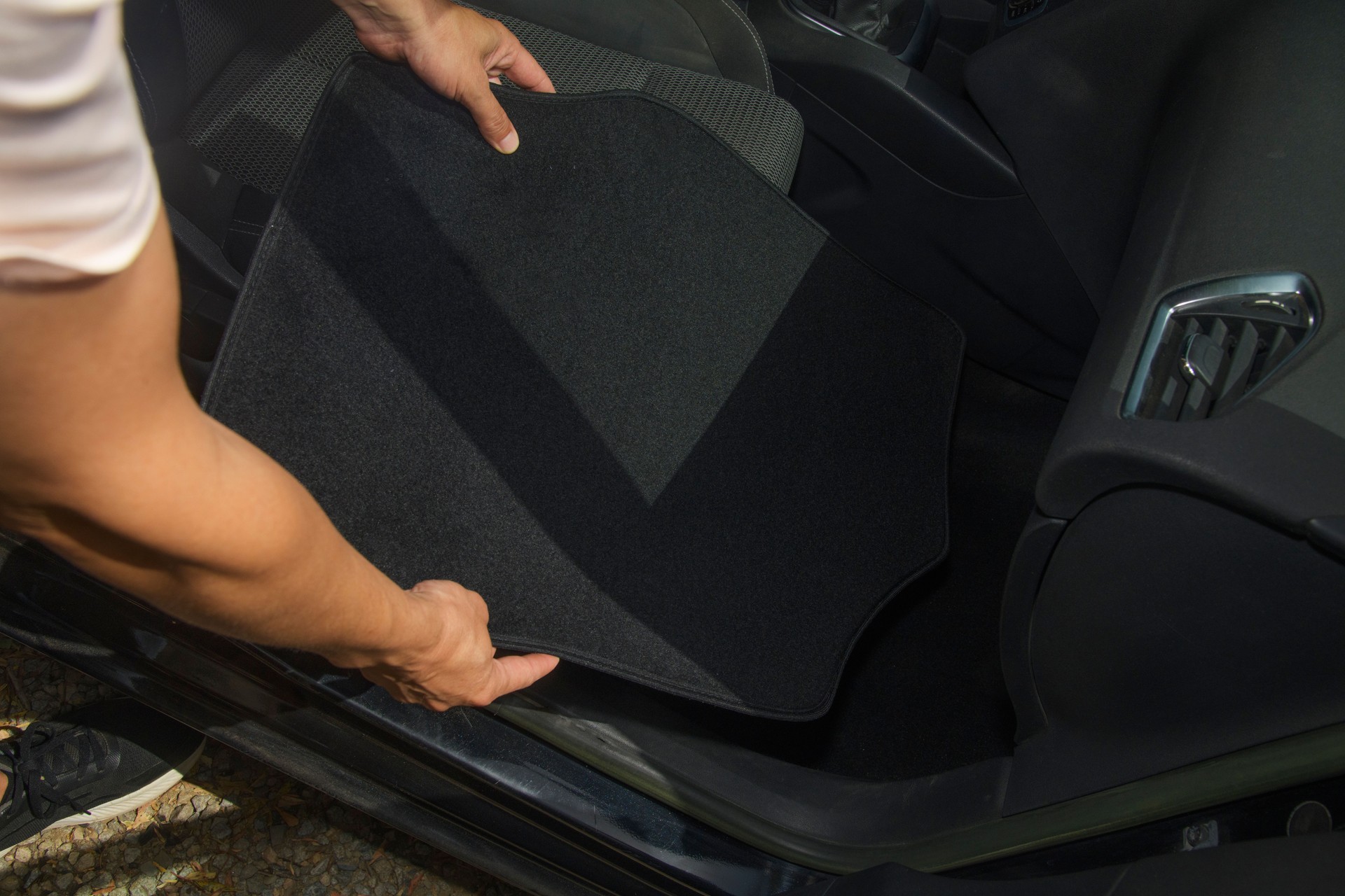 a man places a new mat onto the car floor